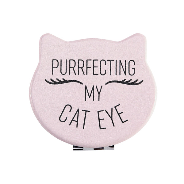 Front view of the Compact Kitty Mirror shaped as a cat head. Outside of mirror is pink and has black writing saying: Purrfecting my Cat Eye