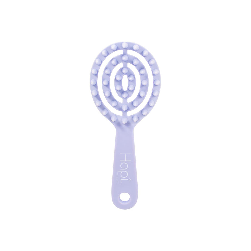 five Hapi hair care tools are shown on a white background: a lavender spiral detangling brush, a mint green wide-tooth comb, a pink paddle brush being held in a hand, and a pink round brush. A hand with pink nail polish is visible holding the pink paddle brush.
