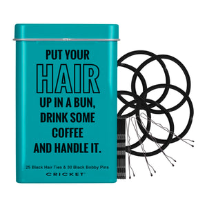 A turquoise metal tin with black text reading 'PUT YOUR HAIR UP IN A BUN, DRINK SOME COFFEE AND HANDLE IT.' next to a bundle of black hair ties and black bobby pins on a white background.