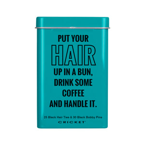 A teal metal tin with a lid and black text that reads, 'PUT YOUR HAIR UP IN A BUN, DRINK SOME COFFEE AND HANDLE IT.' Small text at the bottom says '25 Black Hair Ties & 30 Black Bobby Pins' and the brand 'CRICKET' appears below.