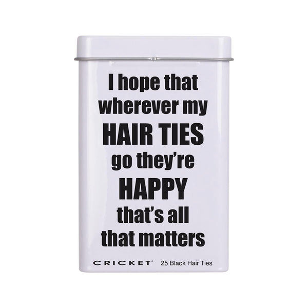 A white rectangular tin with a lid  featuring the humorous text 'I hope that wherever my HAIR TIES go they're HAPPY that's all that matters' in bold black lettering. The brand 'CRICKET' is printed at the bottom along with '25 Black Hair Ties'.