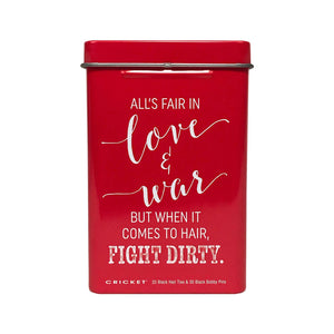 A red rectangular metal tin with a lid, featuring white printed text that reads, 'ALL'S FAIR IN love & war BUT WHEN IT COMES TO HAIR, FIGHT DIRTY.' Small text at the bottom reads 'CRICKET' and '25 Black Hair Ties & 30 Black Bobby Pins.
