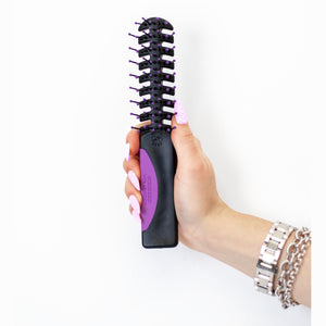 A hand holding Static Free Volumizer Vent Hair Brush in Purple