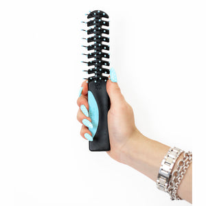 A hand holding Static Free Volumizer Vent Hair Brush in Blue